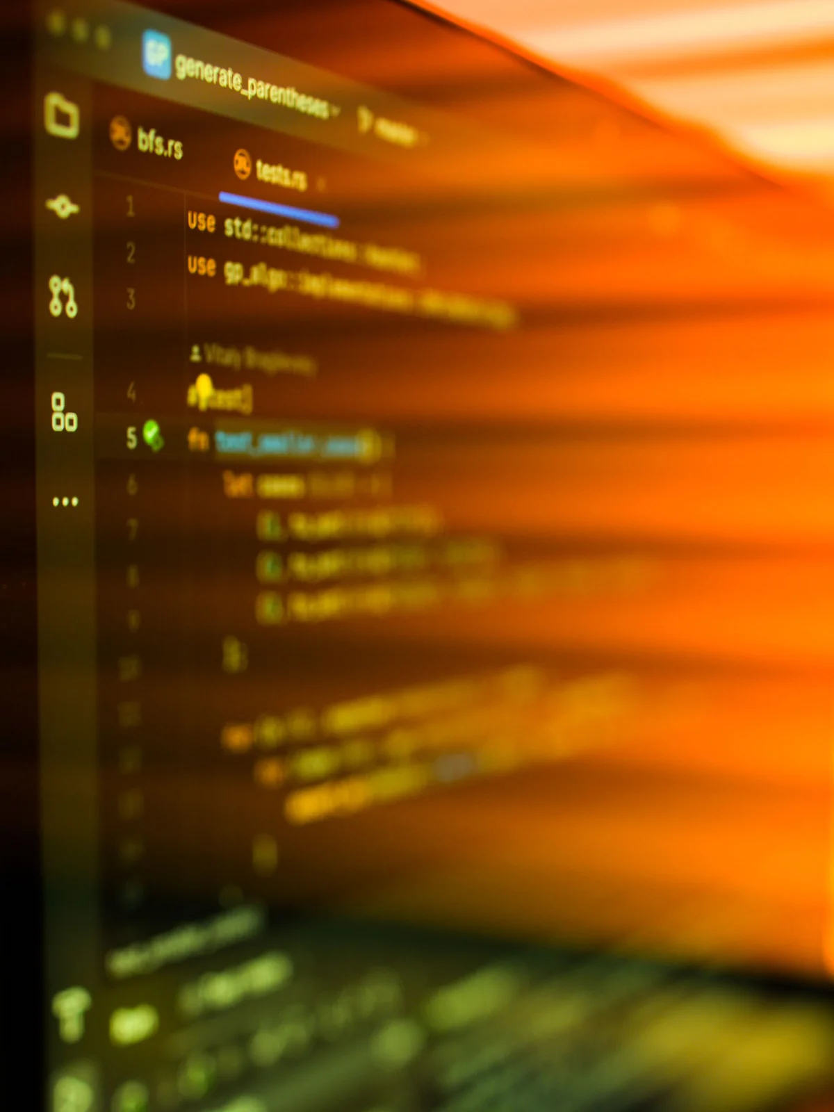 Lignes de code d’un logiciel sur un écran d’ordinateur, traversées par les ombres orangées d’un store au soleil couchant.